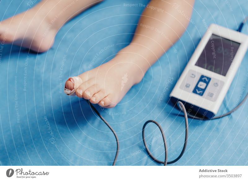 Doctor with oximeter examining little patient medical equipment sensor oxygen doctor kid examine check using pulse hospital clinic respiration control toe child