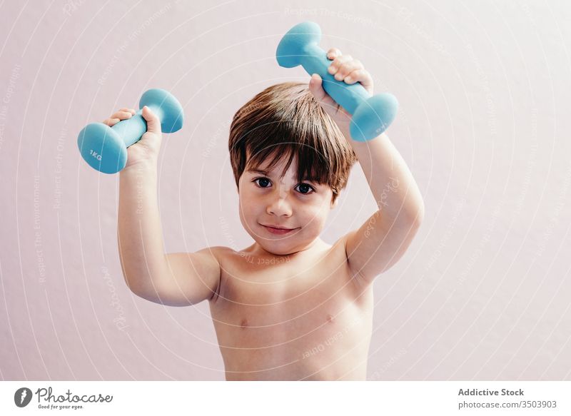 Cheerful little boy with dumbbells kid healthy happy active smile cheerful energy positive child exercise lifestyle joy training childhood glad health care