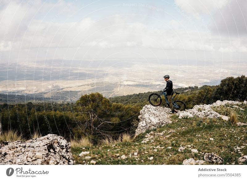 Cyclist riding bike on rocky path in forest man bicycle ride tree travel cyclist helmet trip journey activity recreation route vehicle transport lifestyle