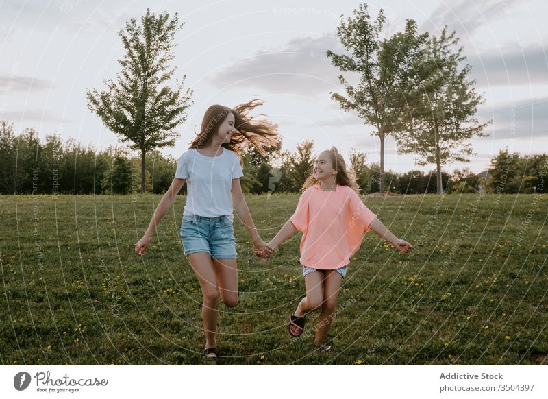 Happy sisters having fun in summer countryside kid nature together happy girl cheerful run teen teenage green meadow sibling friend smile relationship field joy