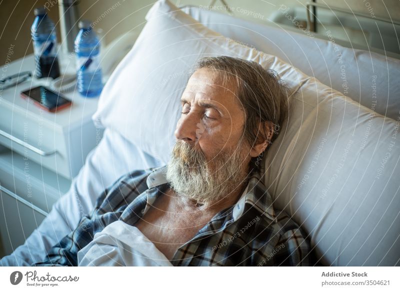 Senior man sleeping in hospital bed senior ward elderly patient medicine illness tired clinic old blanket recovery disease control age unwell problem