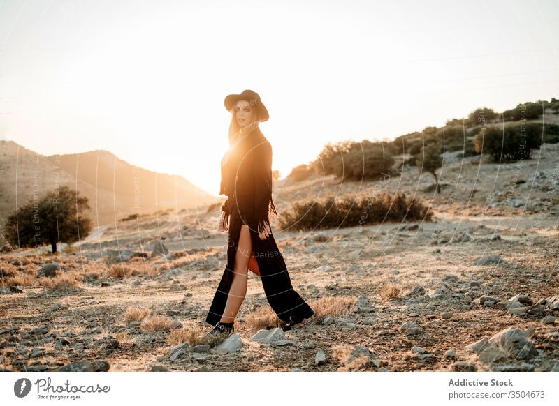 Stylish woman standing on rock in countryside style stone sunset hat walk outfit slime female model black trendy nature boulder sundown evening twilight dusk