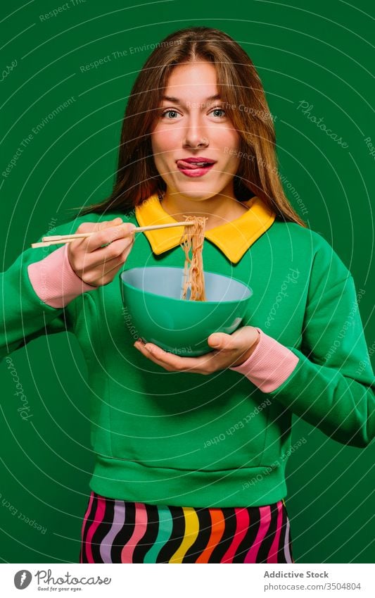 Happy young woman eating noodles instant color happy yummy lick hungry positive female chopstick bowl food smile delicious tasty expressive delight enjoy