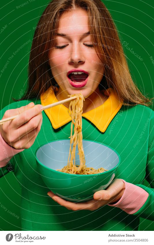 Happy young woman eating noodles instant color happy yummy hungry positive female chopstick bowl food smile delicious tasty expressive delight enjoy fast food