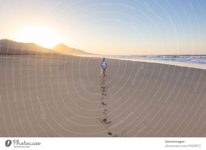 Lady walking on sandy beach in sunset. woman vacation footstep footprint sea water nature summer landscape female beautiful ocean barefoot person coast holiday