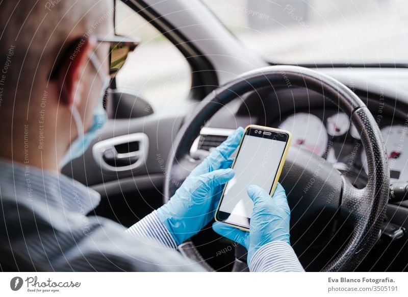 man using mobile phone in a car wearing protective mask and gloves during pandemic coronacirus covid-19 driving protective gloves virus coronavirus technology