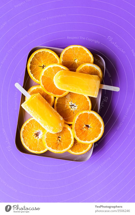 Orange ice cream popsicles on purple background above view childhood citrus classic cold colorful colors contrast cut out delicious dessert flavor food freeze