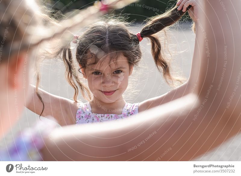 Two sisters play games Child girl playtime Smiley happy hair Sun Summer Portrait photograph eyes