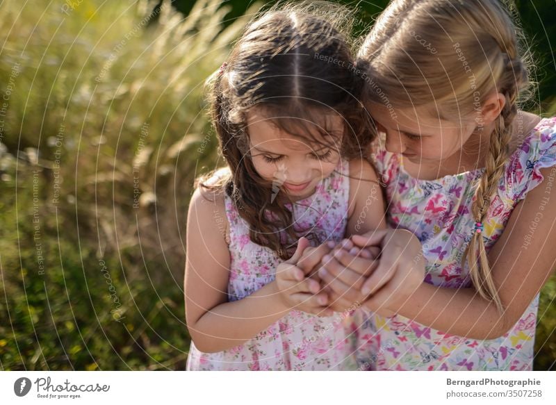 Two sisters play games Summer Light hair smile mystery playtime hands girls