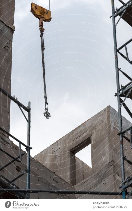 Crane hooks and scaffolding in front of an unfinished building apartment architecture built Business city concrete construction crane design development door