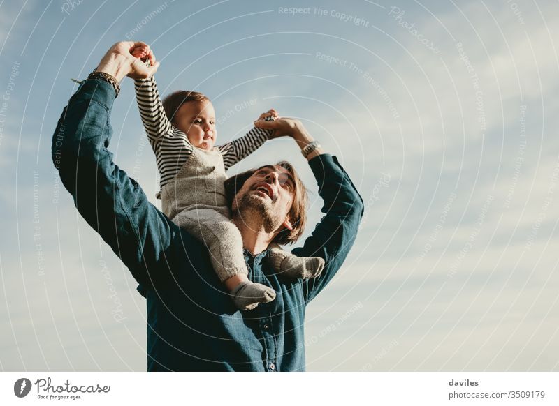 Handsome man giving a piggyback ride to his baby son outdoors. together stroll spring smiling parenting little happiness childhood face care adorable portrait