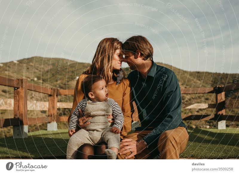 Lovely couple caring to their baby son with mountains in the background. parenthood boy holding romantic hugging dad mom lookout care trip leisure relationship