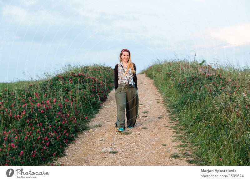 Young female adventurer walking in the fields of Tuscany, Italy adult camera casual cheerful country countryside enjoying europe evening explorer flowers