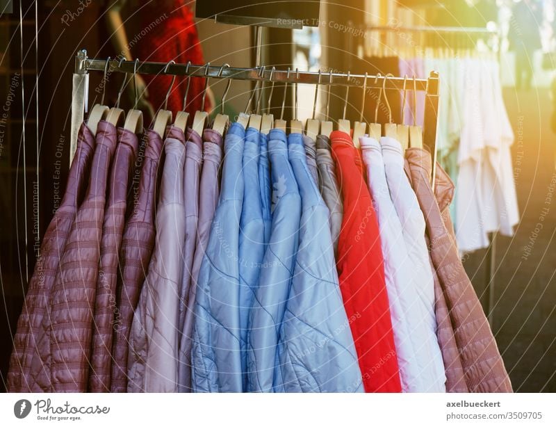 clothes rack with ladieswear spring fashion jackets hanging outside store clothing shop display pastel sun flare light leak retail collection style hanger