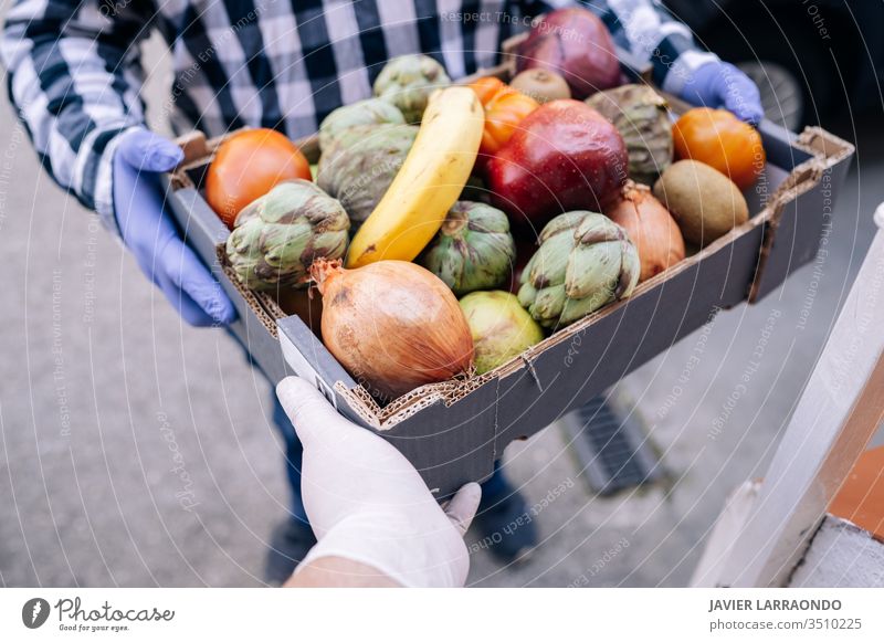 Caucasian volunteer man gives the box from grocery store to a woman at her home.Both with medical gloves.Volunteer and delivering concept aid assist assistance