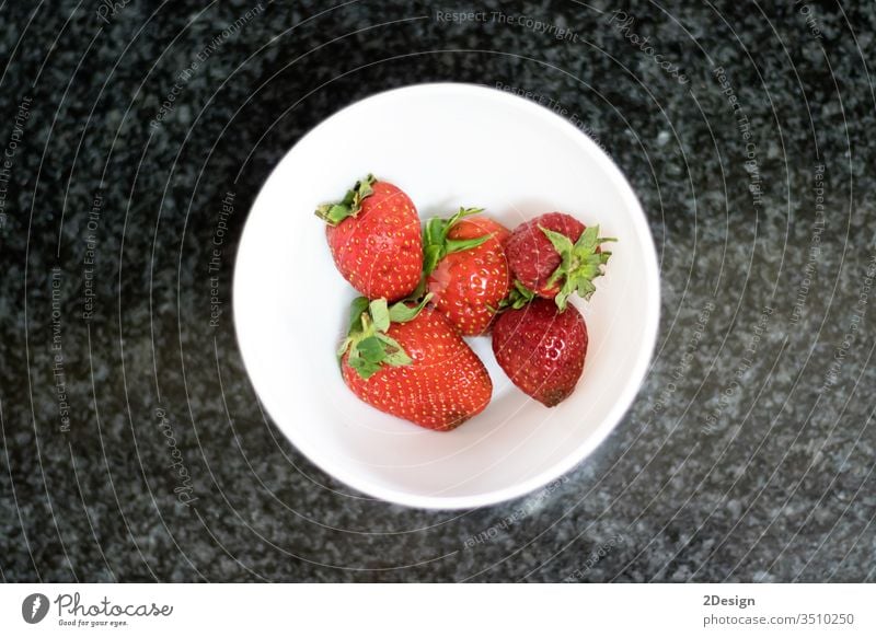 Top view of strawberries over dark marble rural closeup sweet juicy dessert bowl light white vegetarianism fresh nourishment spring season fruit diet berry red