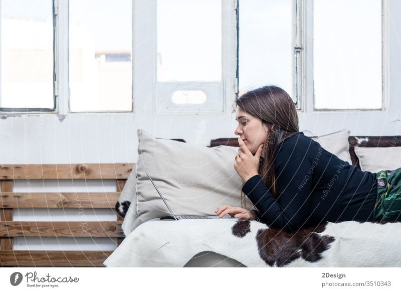 Woman sitting on sofa and using laptop. caucasian woman 1 adult female couch computer person young technology room beautiful living room smile girl relaxation