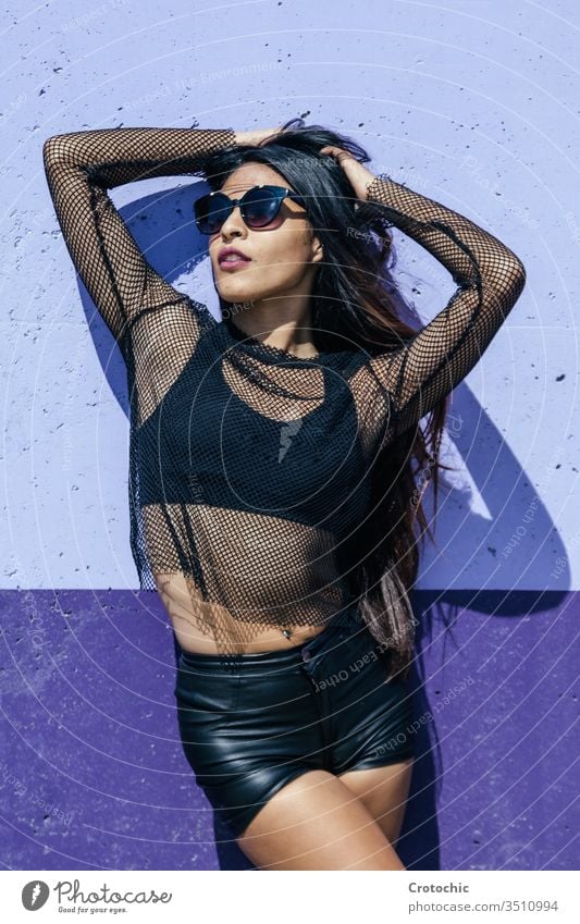 Brunette girl posing as a model in front of a blue wall color black railing fashion mesh sunglasses sunbath beauty erotic graceful hide seductive sex skin