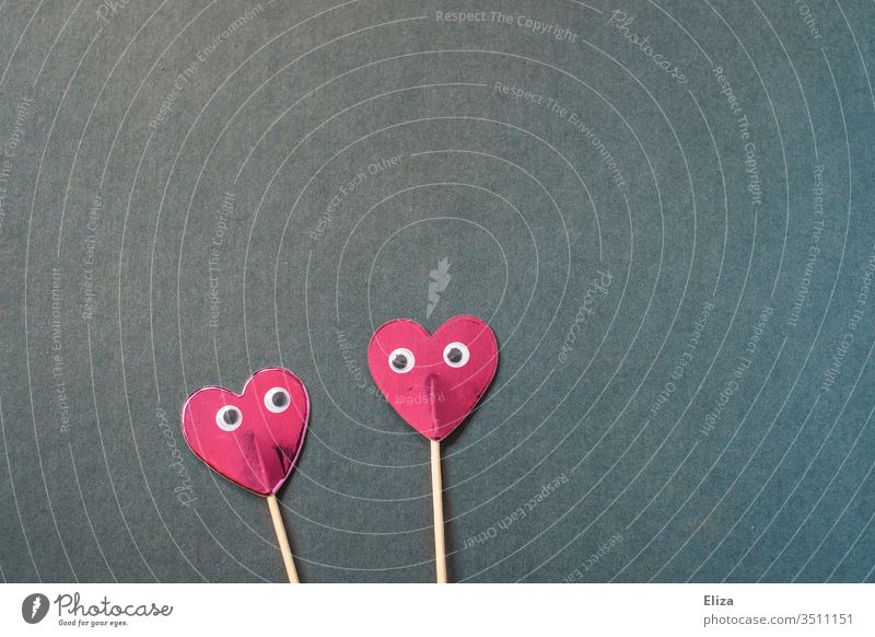 Two pink hearts on a stick with eyes that look at each other cuddle two handle peer wobbly eyes In love Love Emotions Blue Pink Red Valentine's Day Couple Heart