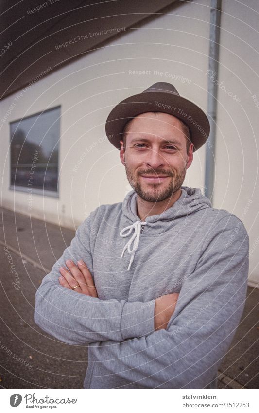 Young man with hat and crossed arms youthful Looking into the camera portrait Hat little hat locked hoodie Sweater Hooded sweater Wedding band Married