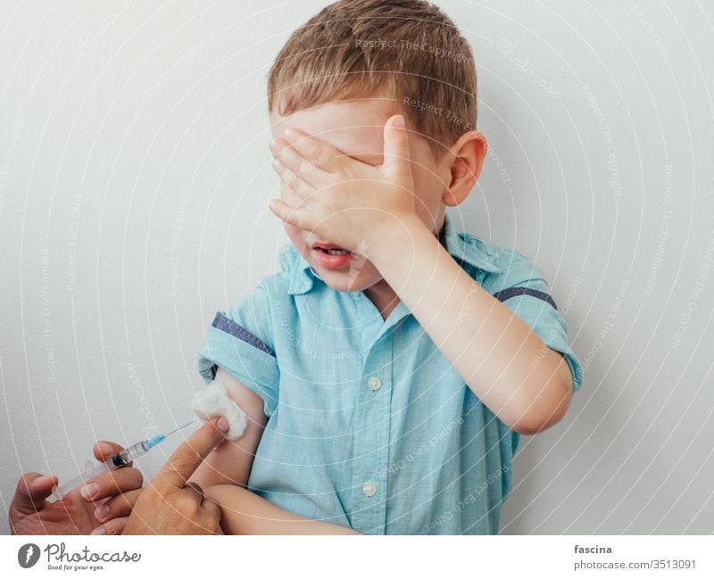 Little boy is afraid to vaccinate little vaccine caucasian injection kid white covered eyes blue shirt hand during vaccination children concept pediatrician