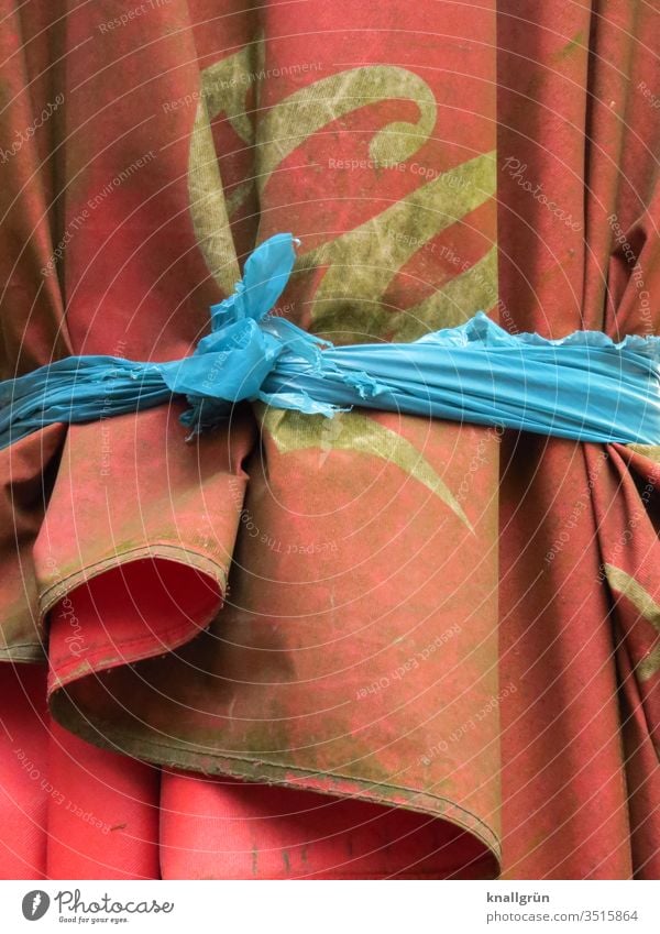 Dirty red parasol tied together with a blue strip of fabric Sunshade Interconnected Red frowzy Knot knotted Blue White Exterior shot Colour photo Detail