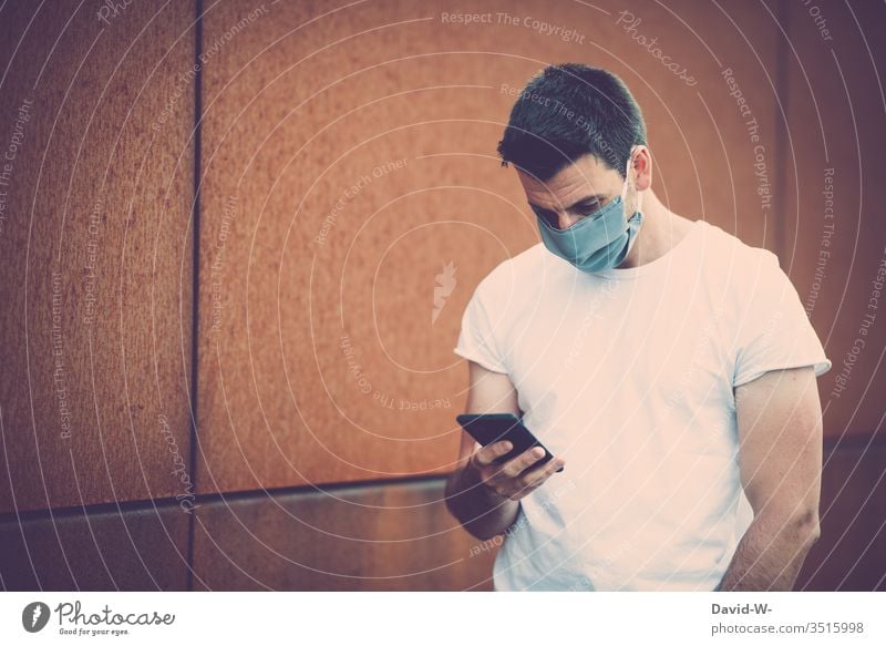 Corona - Man with mobile phone in his hand Respirator mask coronavirus Virus Reading Manipulation message transmission Self-made Mask Write Illness Healthy