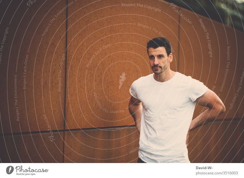 Man with white T-shirt in front of bronze background Bronze Orange White youthful Attractive hunk of man natural Cool cool Congenial adult more adult