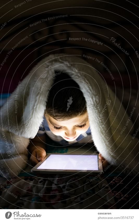 Little child using a tablet covered with a blanket alone application bed bedroom bedtime boy childhood children only children playing communication computer