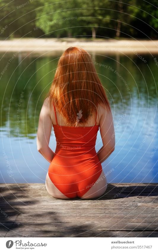 rear view woman wearing red bathing suit sitting on wooden pier swimming lake girl jetty swimsuit back backside bathing costume behind unrecognizable person