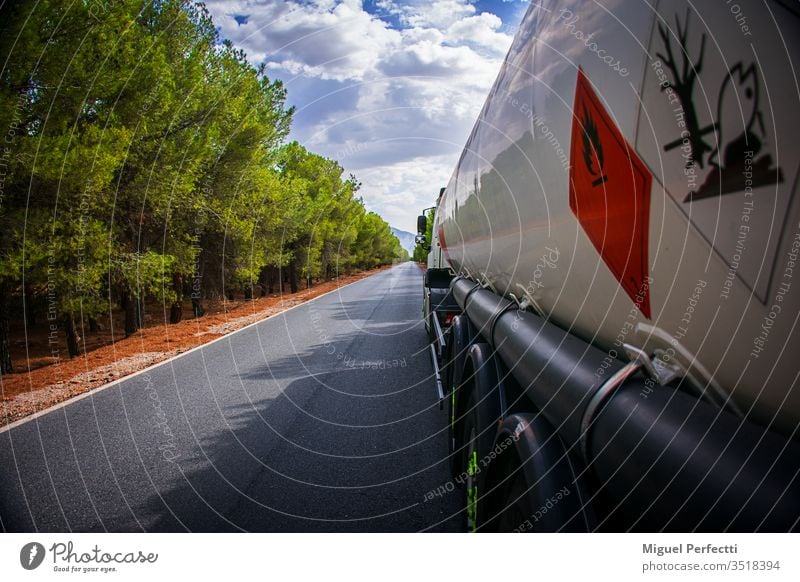 Tank truck with dangerous goods camion cisterna mercancias peligrosas carretera arboles circular placas de peligro inflamable contaminante nubes