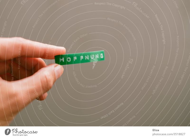 A person holds a green sign with hope written on it in his hand Hope Climate nature conservation by hand stop Word Text Letters (alphabet) writing Label