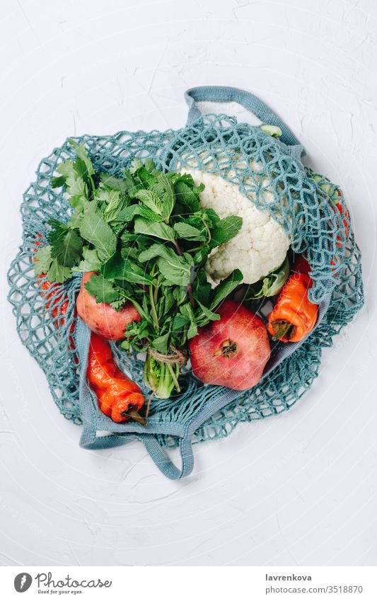 Flatlay of zero waste sustainable food shopping, various fruits, vegetables and greens in a blue mesh bag eating ingredient lifestyle cauliflower chilli