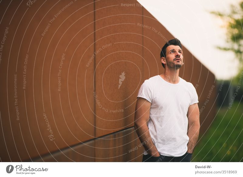 Man with his hands in his pockets looks at the sky trouser pockets Trouser pocket Upward Sky Shadow Light Model white t-shirt muscle muscular Hope Belief Fear