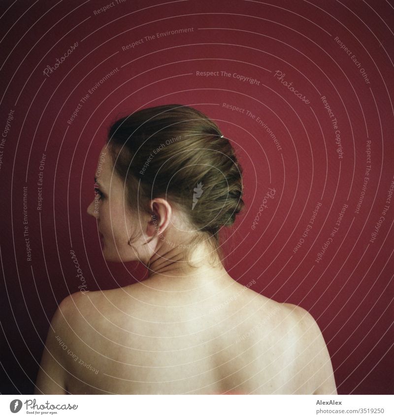 Analogue portrait in rear view of a young woman in front of a red wall Delicate Shadow Light picture-like Athletic Feminine empathy Emotions emotionally