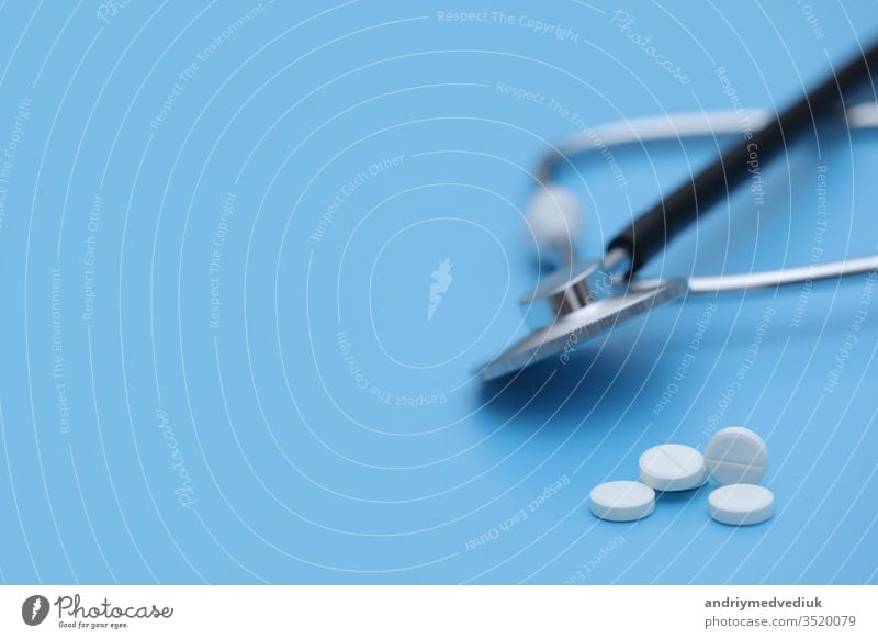 Pills spilling out of pill bottle syringe thermometer and stethoscope on blue background. medicine concept. selective focus medical treatment health white