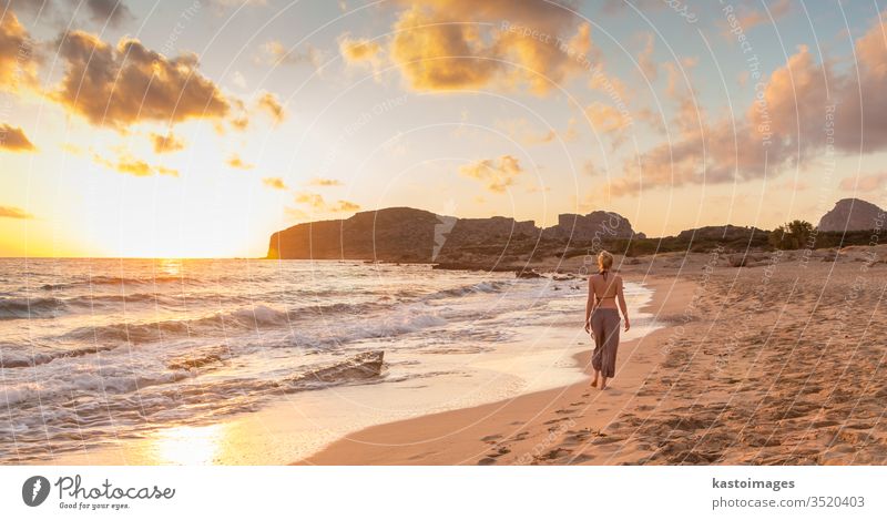 Woman walking on sandy beach at sunset. summer woman female young sea water nature relaxation girl person Falasarna vacation beauty outdoors beautiful alone