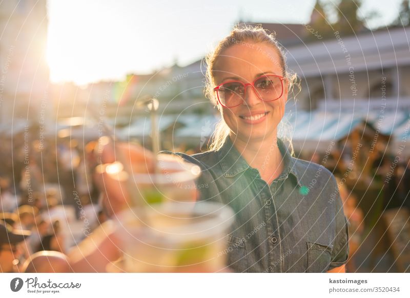 Beautiful young girl toasting on outdoor urban event. festival drink woman people music alcohol fun happiness outdoors youth city smiling celebration cheers