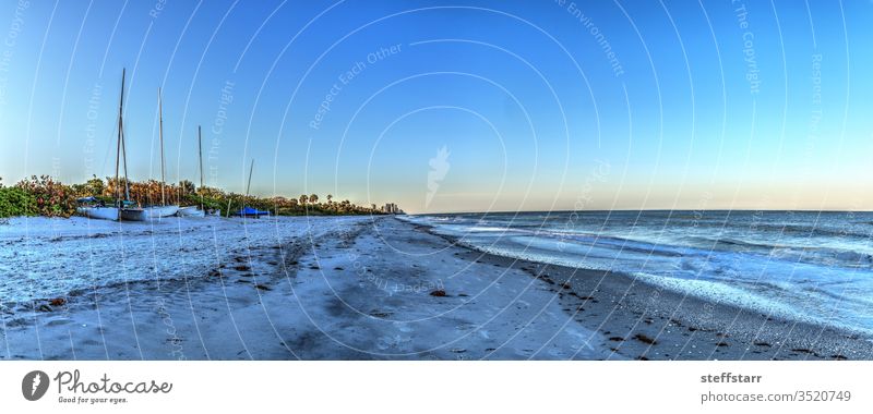 Sunrise at Vanderbilt Beach along the Gulf Coast Sailboat sloop catamaran vessel schooner ship daybreak dawn Coastline coastal beach sand ocean sea blue sky