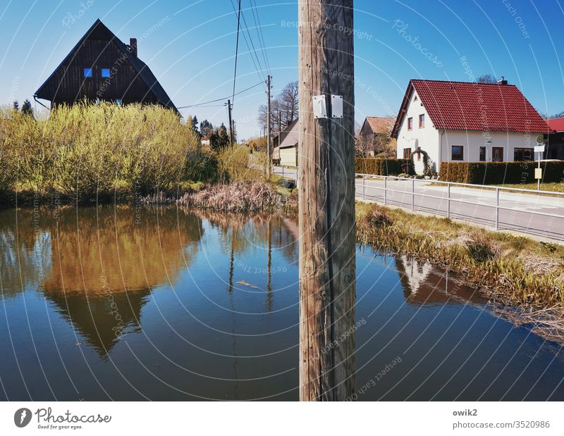 idyllic village pond Village Lausitz forest Saxony houses Street Electricity pylon Lake Water reflection Reflection Handrail Sky Cloudless sky windless