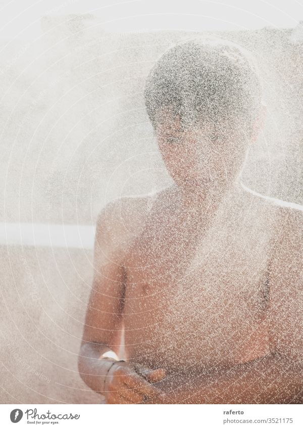 Cheerful young male enjoying a shower by hose outdoors in the terrace boy water garden summer outside children play refreshment pour fun childhood smiling youth