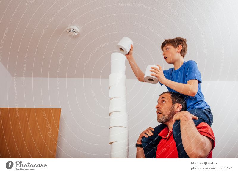 Father and son balancing stacks of toilet paper left Stack Toilet paper Balance Boredom Boy (child) challenge Child Corona covid-19 Epidemic Family game Tall