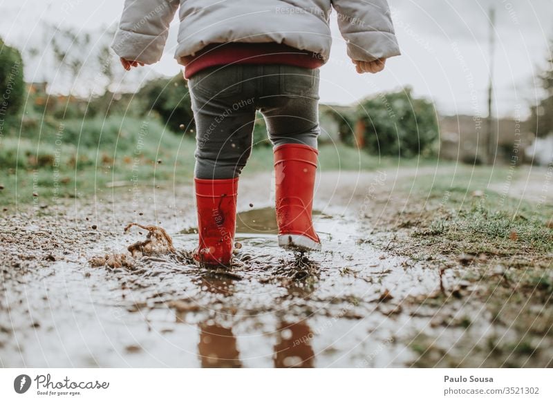 Low Section Of Baby Girl Walking On Puddle During Rainy Season Child Water Reflection Exterior shot Red Rubber boots childhood Happiness Wet Colour photo