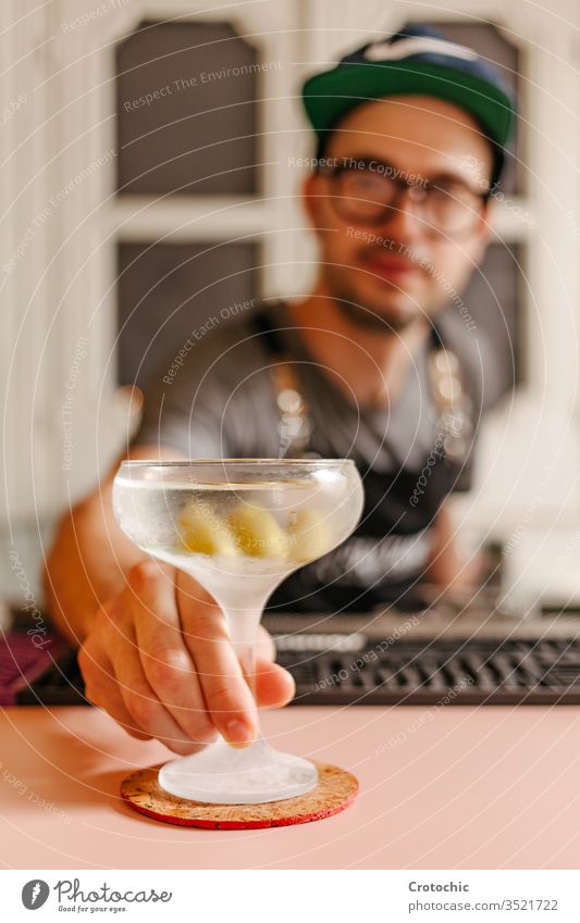 Selective focus in an iced cocktail glass filled with liquid vertical show serve ready alcohol bar modern glasses frost apron waiter hotel fresh restaurant