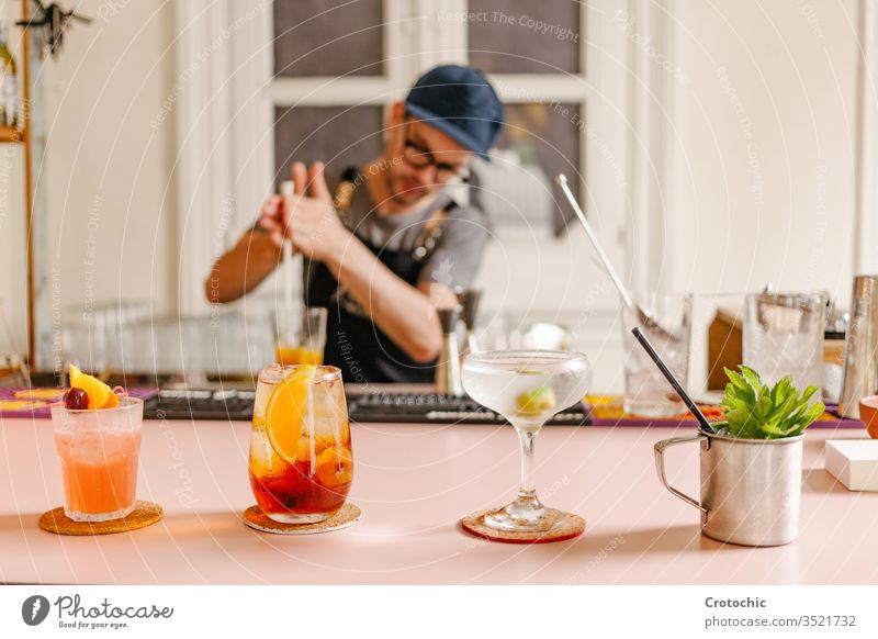 Selective focus in three cocktail glasses prepared with a metal cup with mint on the side at a bar set raw variety selective serve ready alcohol modern liquid