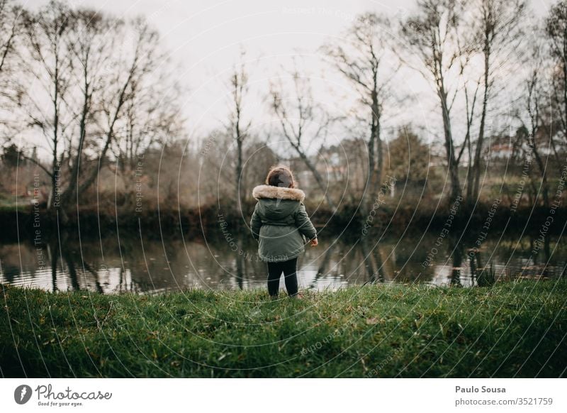 Child looking at river River Curiosity Innocent Nature Rear view Autumn Winter fall Exterior shot Leaf background fragility Tree colorful nature Colour Plant