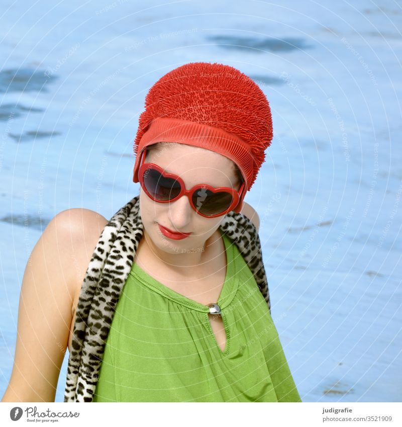 The girl with the beautiful red bathing cap and green swimsuit is sunbathing in the empty non-swimmer's pool. A summer love. Girl Woman Swimwear Bathing cap