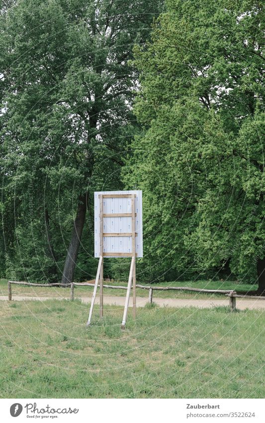 Back of a building sign on a natural meadow in front of a low fence construction sign Rear side Meadow Nature huts Fence off Landscape Construction site green