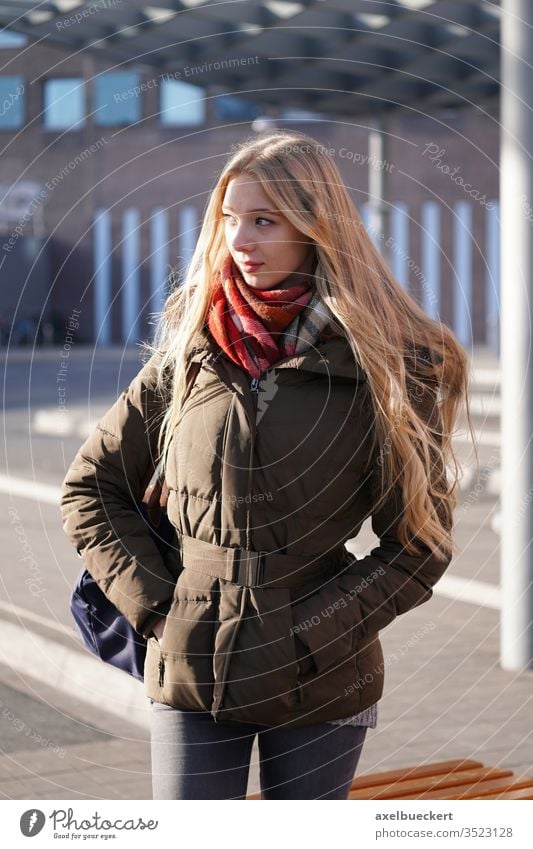 candid street style image of young woman waiting at bus station girl stop teenager real people portrait city urban lifestyle winter outside blond blonde long