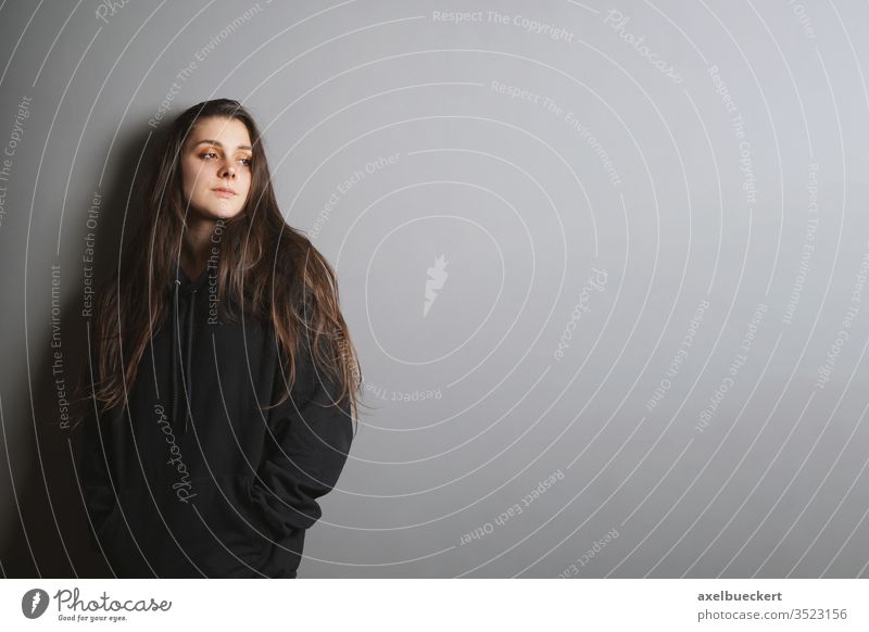 sad young woman leaning against wall looking to side in contemplation girl goth thinking teenager adolescence youth sadness depression melancholy looking away